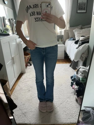 Blå bootcut jeans med broderade fickor - Säljer ett par klassiska blå bootcut jeans med snygga broderade detaljer på bakfickorna. Jeansen har normal midja och är i ett mjukt denimtyg som sitter skönt. Perfekta till en avslappnad och trendig look.