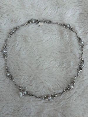 Silverhalsband med pärlor och figurer - Säljer mitt unika och konstnärliga halsband i silverfärgad metall med små figurer som håller i runda vita pärlor med små gnistrande stenar. Så himla fint men kommer sällan till användning för mig. (Från IOAKU) 