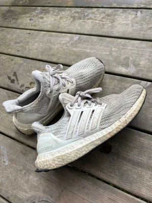 Vita Adidas Ultra Boost sneakers dam 38 - Säljer ett par Adidas Ultra Boost sneakers med stickad ovandel och vita detaljer. Skorna har den klassiska Boost-sulan för extra komfort och svarta yttersulor. Perfekta för dig som gillar stilrena och bekväma sneakers med sportig känsla. Storlek 38