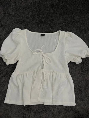 Vit blus med puffärm och knyt - Säljer denna vita blus då den inte används nått! Oanvänd bara provad någon gång. Annars har den bara legat orörd i garderoben