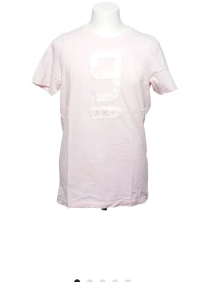 Ljusrosa t-shirt med tryck - Säljer en ljusrosa t-shirt med ett stort vitt tryck av siffran 9 och texten A&F på bröstet. T-shirten har rund halsringning och korta ärmar. Tillverkad i mjuk bomull för en skön känsla.