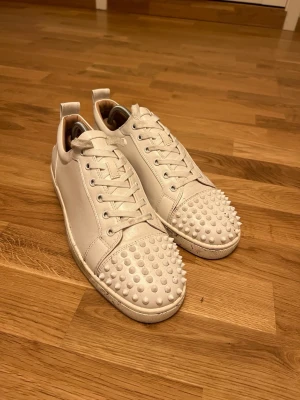 Christian Louboutin - Storlek 46 - Säljer ett par vita sneakers i storlek 46. Sparsamt använda och överlag i fint skick.  * Storlek: 46 * Färg: Vit * Sparsamt använda * Kartong och kvitto saknas  Skick enligt bilder. Säljs i befintligt skick.