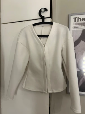 Vit minimalistisk kofta med v-ringning - Stilren vit kofta med v-ringning och lång ärm. Koftan har en rak passform och är tillverkad i ett mjukt, tjockare material som ger en clean look. Perfekt för dig som gillar enkel och modern stil. Från ZARA men lappen är borta🥰