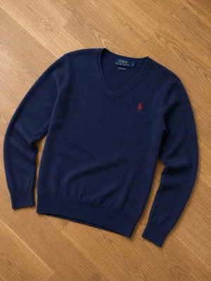 Mörkblå tröja Ralph Lauren - Mörkblå tröja från Polo Ralph Lauren med röd broderad logga på bröstet. Tröjan har långa ärmar, ribbade muddar och är tillverkad i ett mjukt material som passar perfekt till jeans.