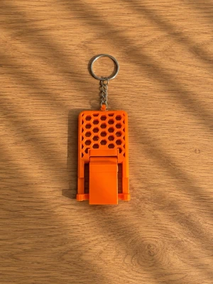 Nyckelring med mobilställ i plast - Snygg och praktisk nyckelring med inbyggt mobilställ. Stället har ett coolt hexagonmönster och finns i orange och grönt. Perfekt att ha med sig för att enkelt ställa upp mobilen när du kollar på videos eller snackar med kompisar. Tillverkad i tålig plast och metall.