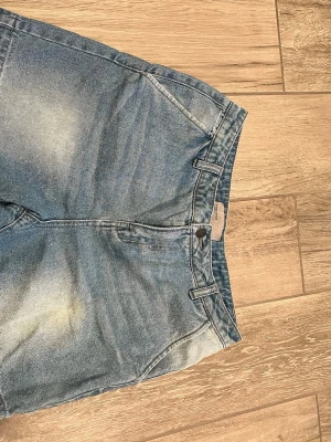 Blå jeansshorts från Vero Moda - Säljer ett par klassiska blå jeansshorts från Vero Moda. De har normal passform, fem fickor och bälteshällor. Materialet är slitstark bomull med snygg tvättad effekt. Perfekta till sommaren och enkla att matcha med olika toppar.