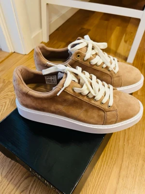 Beige mockasneakers med vita sulor - Snygga sneakers i beige mocka med vita, tjocka gummisulor och vita skosnören. Helt nya och oanvända, perfekta till hösten. Kostar 1599kr, säljs för 950kr. Storlek 8.5B (39/40) 