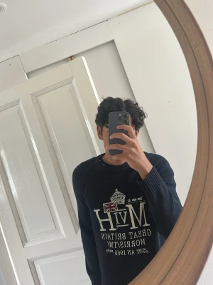Mörkblå tröja från Morris Gents - Snygg mörkblå tröja från Morris med tryck framtill som inkluderar brittisk flagga och text. Tröjan har rund halsringning och ribbade muddar vid ärmslut och nederkant. Perfekt för en stilren och avslappnad look.