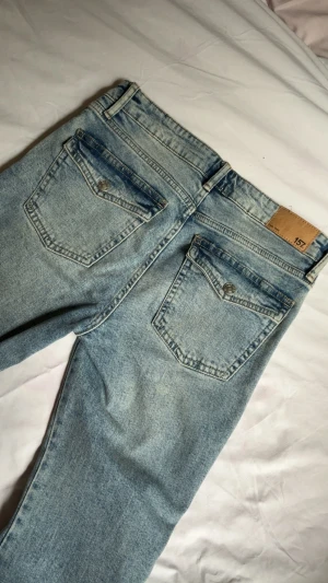 Jeans 90’s bootcut Lager 157 - Ljusblå jeans i 90’s bootcut stil från lager 157. Säljer då de inte används mycket. Tyget är lite upptrampat på slutet av benen då jeansen är för långa på mig, men har bara använt dem 2-3 gånger. Sista bilden är från hemsidan och visar passformen, artikelnummer: 15531. Men jag tror att den här färgen inte säljs längre. 
