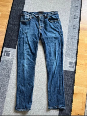 Nudie jeans Grim Tim - Säljer ett par klassiska grim Tim från Nudie Jeans Co. Jeansen har rak passform, fem fickor och snygga kontrastsömmar. Tillverkade i slitstarkt denim med en tidlös look som passar till det mesta. Perfekta för dig som gillar stilrena och bekväma jeans.
