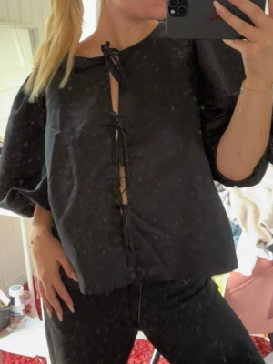 Svart blus med puffärmar och snörning - Svart blus med puffiga långärmar och snörning framtill. 