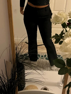 Svarta kostymbyxor från Bik Bok - Svarta kostymbyxor från Bik Bok i storlek 38. Byxorna har hög midja, raka ben och klassisk passform med bälteshällor och diskret dragkedja framtill. Materialet är mjukt och har en lätt stretch för extra komfort. Perfekta för en clean och stilren look.