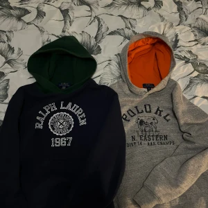 Två ralph lauren hoodies  - Två stycken polo ralph lauren hoodies med unikt tryck på magen en blå och grön och den andra grå och orange båda är i storlek Junior L (14-16år). Du får båda hoodiesarna i ett paket för 1200 spänn pris går att diskutera.