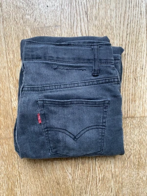 Levi's 512 Slim Taper jeans mörkgrå - Säljer ett par Levi's 512 Slim Taper jeans i mörkgrå färg. Modellen har smal passform med avsmalnande ben, klassiska fem fickor och dragkedja. Jeansen är tillverkade i mjukt denimtyg med snygga slitningar för en cool look.