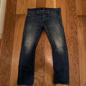 Replay waitom jeans blå tapered - Snygga Replay waitom jeans i mörkblå tvätt med slitningar och klassiska fem fickor. Tapered passform som sitter skönt och ger en modern look. Jeansen har detaljerade bakfickor och är tillverkade i slitstarkt denim-material. Hål i högra knäet