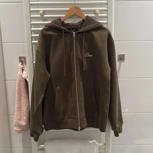 Olivgrön hoodie från Dime med dragkedja - Olivgrön zip hoodie från Dime med broderad logga på bröstet. Storlek M passform 175-185cm långa. Aldrig använd, köpt i Canada i somras. Finns inte att köpa i Sverige.