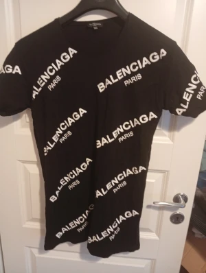 Svart t-shirt XXL - Svart t-shirt i storlek XXL (känns mindre i storlek dock) med vit logotypprint över hela plagget. Klassisk rund hals och korta ärmar. Materialet är mjuk bomull som känns skönt mot huden. Perfekt för dig som gillar streetwear