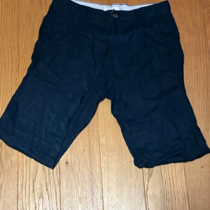 Mörkblå linne byxor W31 - Snygga mörkblå shorts i linne med klassisk passform och midwaist. De har knapp och dragkedja framtill samt praktiska fickor på sidorna. Perfekta för varma dagar och ger en chill vibe till din outfit. Ökänt märke, säljer pågrund av att dem är för små rensar min garderob!
