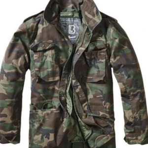 Camouflagejacka från Brandit - Säljer en cool camouflagejacka från Brandit med avtagbart innerfoder. Jackan har en klassisk militärlook med dragkedja och knappar framtill. Perfekt för utomhusaktiviteter och har en praktisk design med flera fickor och mycket detaljer. Jackan är sprillans ny och helt oanvänd! Hör av er om ni har frågor eller om ni vill byta något😇