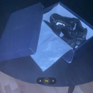 Ett par CB 30b skor  - Säljer ett par svarta sneakers med reflekterande detaljer och CD-logga på hälen. Skorna har en chunky platt sula, snörning och meshpartierk för extra komfort. Snygg design med grå och silverfärgade inslag som ger en modern vibe.