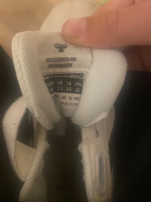 Vita Hummel sneakers strl 35 - Säljer ett par vita Hummel sneakers med svarta detaljer och gummisula. Skorna har klassisk snörning och är tillverkade i mesh och syntetmaterial för bra ventilation. Snygg sportig design med Hummels ikoniska pilar på sidan. Perfekt för dig som gillar stilrena och bekväma skor.