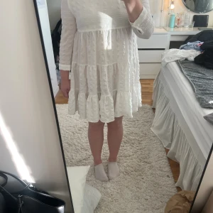 Vit volangklänning  - Säljer en vit kortklänning med volanger och struktur i tyget. Klänningen har rund hals, trekvartsärmar och en luftig känsla. Materialet känns lätt och har en snygg textur som gör klänningen extra fin!!💕✨