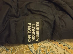  Burberry puffer  -  Burberry puffer med avtagbara ärmar så den kan användas som väst. Jackan har huva med rutigt foder i svart, vitt och rött, dragkedja och knappar framtill samt två fickor med dragkedja. Perfekt för kalla dagar och har en clean, modern look. Prisen kan  diskuteras!!