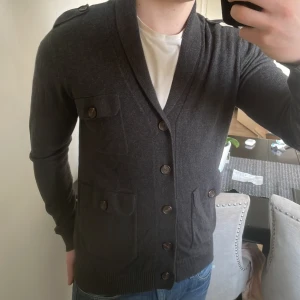 Grå stickad cardigan - Skit fet grå stickad cardigan. Modellen är 180cm, 73kg. Priset kan såklart diskuteras.