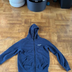 Marinblå hoodie från Replay - Säljer en marinblå hoodie från Replay med dragkedja och huva. Framtill finns en liten logga och baksida en större logga 