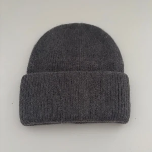 Mörkgrå  mössa - En enkel och stilren mörkgrå mössa med ribbad struktur och uppvikt kant. Perfekt för kalla dagar och passar till de flesta outfits. Materialet är mjukt och stickat för extra komfort och värme.