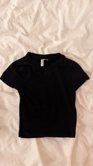 Svart kortärmad t-shirt från H&M - En svart basic t-shirt/magtröja från H&M Divided i storlek XS. Ganska kort vid magen och armarna. Säljer då den aldrig kommer till användning. Skriv privat för mer bilder!!🥰💞