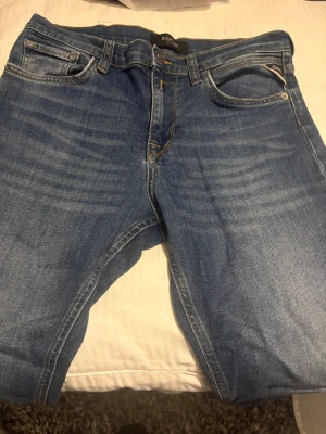 Replay blå jeans straight fit - Blå jeans från Replay med klassisk femficksdesign och snygga slitningar framtill. Jeansen har raka ben och normal passform. Snygg tvätt och ett väldigt bra skick, W 28 L 30
