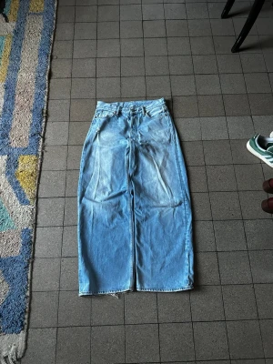 Acne Studios ljusblå 1981m jeans - Säljer ett par ljusblå jeans från Acne Studios med breda ben och råa, fransiga benslut. Klassisk femficksmodell med hög midja och raka sömmar. Jeansen är i mjukt bomullsmaterial och har Acne Studios-logga på knapp och läderpatch bak. Storlek 46 (30/32).