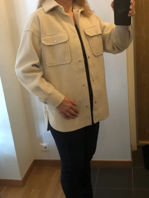 Beige fodrad jacka/overshirt med fickor - Säljer en beige fodrad jacka/overshirt från H&M med två stora bröstfickor och silvriga knappar framtill. Modellen är stor i storleken.