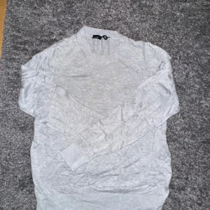 Ljusgrå stickad tröja/kofta - Säljer en stilren ljusgrå stickad tröja från lager 157. Tröjan är i skönt luftigtmaterial som är väldigt mjuk. Endast använd 1 gång!