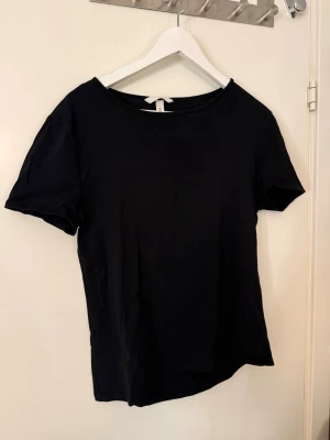 Svart basic t-shirt från H&M - En enkel svart t-shirt från H&M i storlek L. Klassisk rund halsringning och korta ärmar. Tillverkad i mjuk bomull som känns skön mot huden. Perfekt att matcha med jeans eller shorts för en clean look.