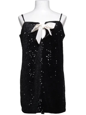 Svart glittrig kortklänning med rosett, nyårsklänning - Svart kortklänning med tunna axelband, täckt av glittriga paljetter och en vit rosett framtill vid halsringningen. Klänningen har en rak passform och är perfekt för dig som vill sticka ut med en glamorös look. Materialet är troligtvis polyester.