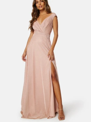 balklänning - Supersnygg långklänning i champagnefärg med glittrigt tyg och v-ringad omlott överdel. Klänningen har en markerad midja, slits på ena sidan och breda axelband. Perfekt för bal eller festliga tillfällen. Materialet känns lyxigt och faller fint Den är yppsydd nertill då den var väldigt lång på mig som är 165,  nuddar fortfarande marken på mig.