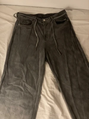 Baggy jeans - Ett par gråa jätte Baggy jeans! Har använts ganska mycket och därför är de tyg som har trampats bort vid hälarna!!