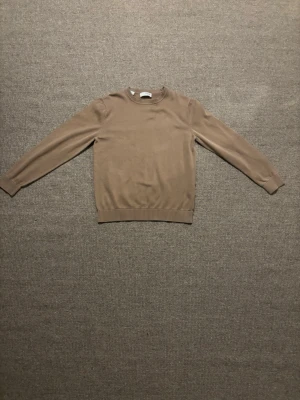 Beige stickad tröja från Selected Homme - Snygg beige stickad tröja från Selected Homme med rund hals och ribbade muddar vid ärmslut och nederkant. Perfekt för lager-på-lager och passar till jeans eller chinos. Enkel och stilren design som funkar året runt.