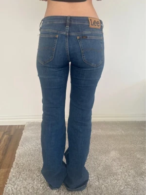 Blå bootcut jeans från Lee - Passar inte mig så väljer att sälja. Snygga blå jeans från Lee med bootcut o lowaist. Slitstarkt jeansmaterial i bomull. Midjemått: 38cm, Innebenslängd: 80cm. Bilder från förra ägaren. Skriv för frågor!! 💓💓