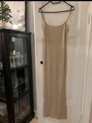 Beige långklänning från SHEIN - Säljer en stilren beige långklänning från SHEIN i storlek XS. Klänningen har smala axelband och är figurnära med rak siluett. Materialet är mjukt och stretchigt, tillverkat av 95% polyester och 5% elastan. Perfekt för dig som gillar minimalistisk och enkel stil.