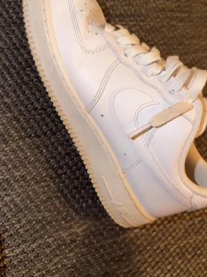Nike Air Force 1  - Helt nya airforces pytte lite crease på framsida men annars ingen fel på dom och lite beige gulaktig färg på under sida. Klassiska Nike Air Force 1 sneakers i helvitt skinn med rund tå och perforerade detaljer på tån. Skorna har tjock vit sula, snörning och den ikoniska swoosh-loggan på sidan. Perfekta för dig som vill ha en clean och tidlös look. 