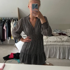 Svart kortklänning med mönster från Zara  - Supersnygg svart kortklänning med vitt mönster och volang nedtill. Klänningen har långärmade puffärmar och går in i midjan. Materialet är lätt och luftigt, perfekt för alla årstider! 🍂☀️