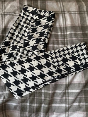 Svarta och vita mönstrade leggings XL - Säljer ett par leggings i storlek XL med ett fett svartvitt mönster. De är stretchiga och sitter skönt. Perfekta för dig som gillar att sticka ut med grafiska prints. Materialet känns mjukt och följsamt mot huden.
