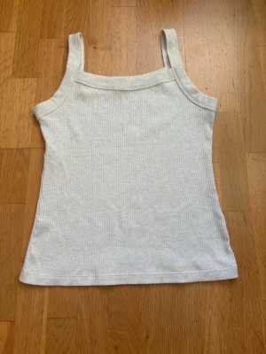 Ribbad vit linnetopp från American Eagle - Säljer en stilren vit ribbad linnetopp från American Eagle i storlek S. Toppen har breda axelband och är tillverkad i mjuk bomull med stretch. Perfekt för varma dagar och enkel att matcha med jeans eller shorts.