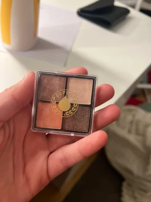 Depend ögonskuggspalett med fyra färger - Säljer en ögonskuggspalett från Depend med fyra skimrande nyanser: koppar, ljusbeige, persika och mörkbrun. Paletten är kompakt och har ett genomskinligt lock med Depend-loggan. Perfekt för att skapa olika looks med både ljusa och mörka toner.