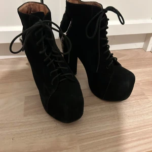 Svarta boots med metallklor och platå - Unika svarta boots med höga klackar och platåsula i mocka. Skorna har snörning framtill och coola silvriga metallklor som detalj runt hälen. Perfekt för dig som vill sticka ut med din stil och gillar edgy accessoarer. Ny pris 1600kr