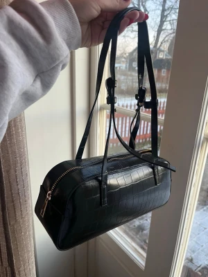 Svart axelväska i croco-mönstrat skinn - Svart väska från Lindex! Använd endast i några timmar då jag hade glömt en liten väska så lära spontan köpa den! Så den är i princip helt Ny!! Nypris 349kr❤️