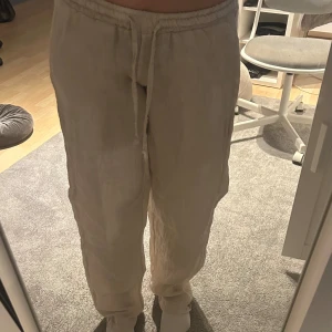 Beige linnebyxor från Chelsea Girls XS - Säljer ett par ljusbeige linnebyxor från Chelsea Girls, tillverkade i Italien. Byxorna har en avslappnad passform med elastisk midja och snörning. Materialet är 100% linne, vilket gör dem luftiga och sköna. Perfekta för varma dagar och chill stil.